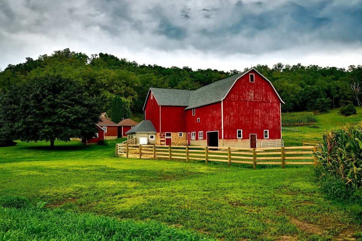 Red barn and green farmland in rural Vermont with wooded hills in the background