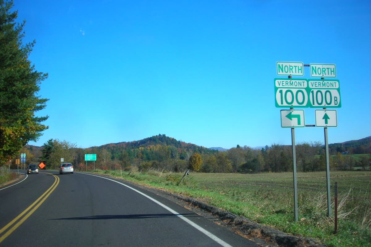 Vermont Route 100 road sign with fall foliage and farmland in central Vermont